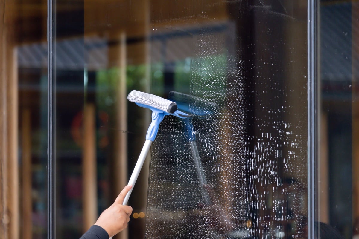 A person cleaning a window with a squeegee