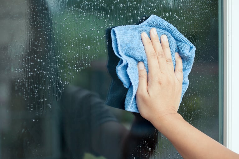 Woman hand cleaning window with rag